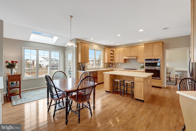 dining space featuring a skylight, visible vents, light wood-type flooring, and baseboards