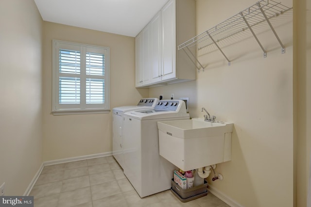 washroom featuring baseboards, washing machine and dryer, light tile patterned flooring, cabinet space, and a sink