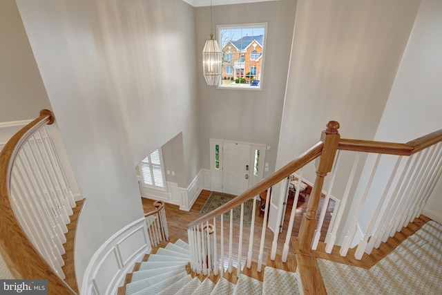 stairs with baseboards, wood finished floors, and a towering ceiling