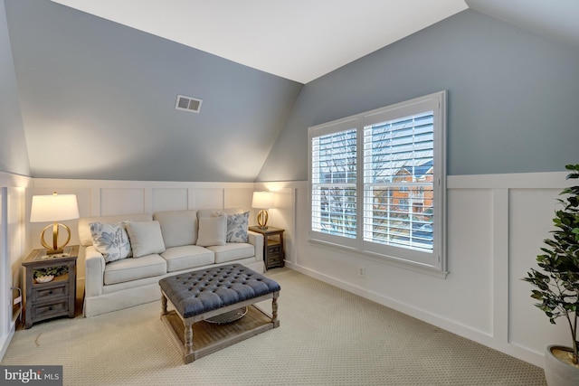 living area with visible vents, carpet, and vaulted ceiling