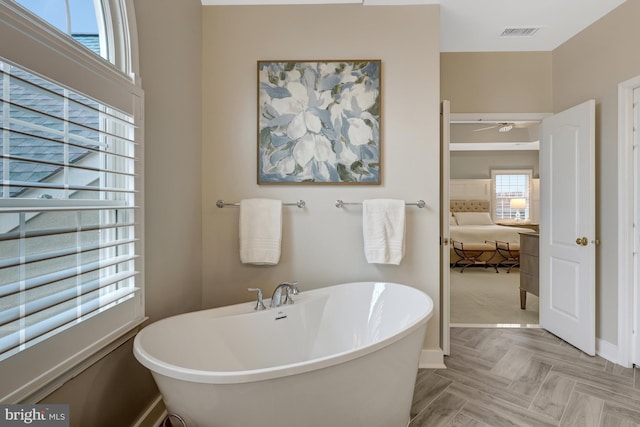 bathroom featuring baseboards, visible vents, and a freestanding bath