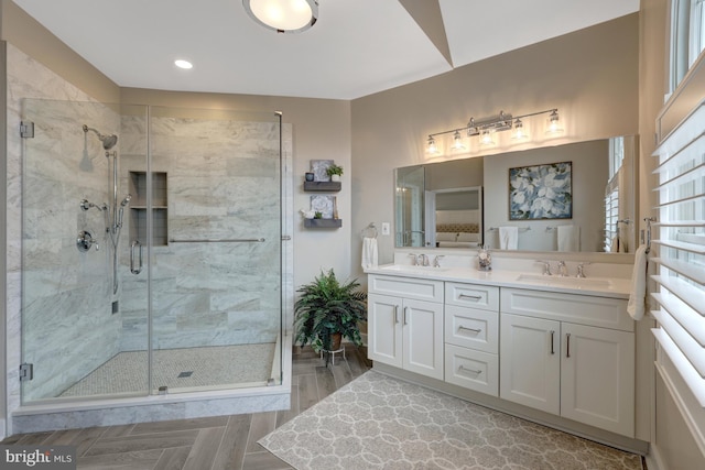 full bath with a shower stall, recessed lighting, double vanity, and a sink