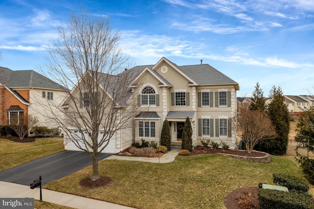 view of front facade with aphalt driveway, an attached garage, a shingled roof, and a front yard