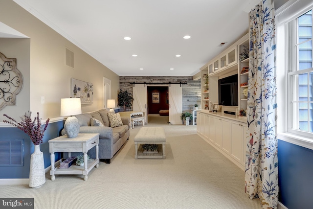 carpeted living room featuring visible vents, recessed lighting, a barn door, and ornamental molding