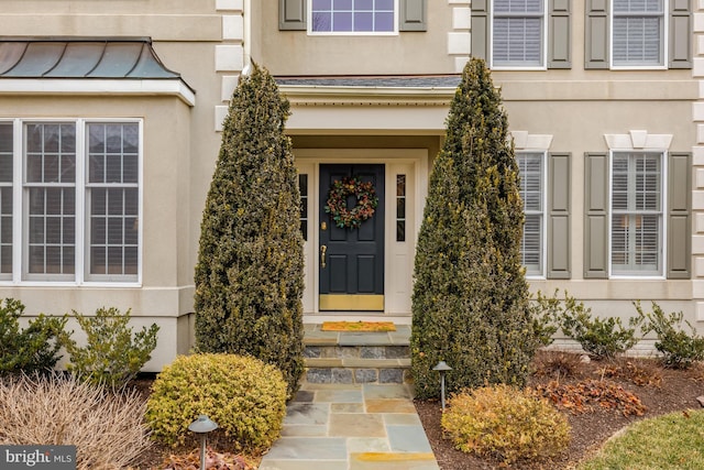 property entrance with stucco siding and a standing seam roof