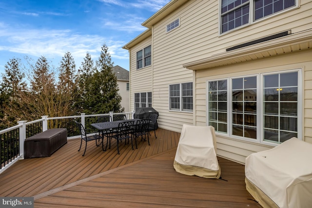 wooden terrace featuring outdoor dining space and grilling area