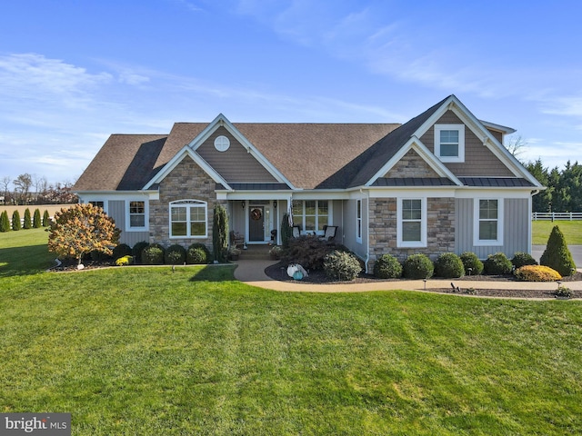 craftsman-style home featuring stone siding, a standing seam roof, and a front yard