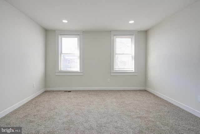 empty room featuring light colored carpet, a wealth of natural light, and baseboards