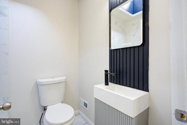 half bath with baseboards, visible vents, a sink, and toilet