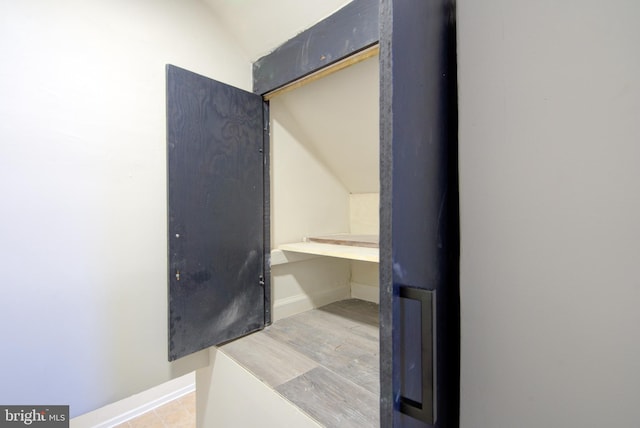 bathroom with lofted ceiling, baseboards, and wood finished floors