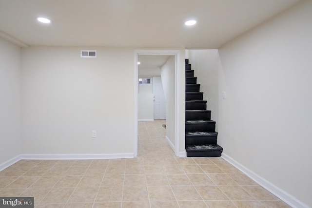 finished basement featuring light tile patterned floors, recessed lighting, visible vents, and stairs