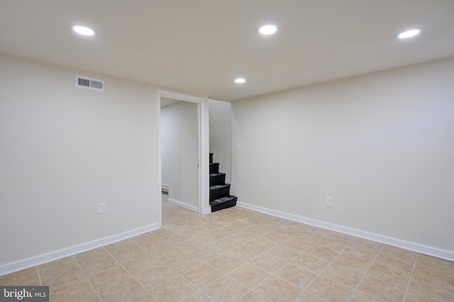 finished basement with stairway, visible vents, and recessed lighting