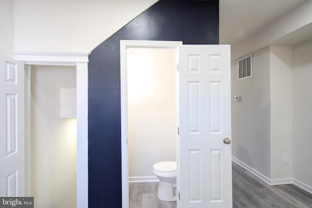 bathroom with toilet, wood finished floors, visible vents, and baseboards