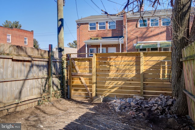 rear view of property featuring a fenced backyard and brick siding