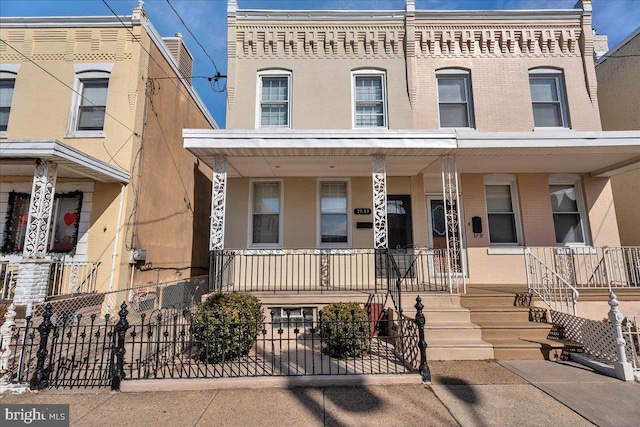 multi unit property featuring a porch, fence, and brick siding