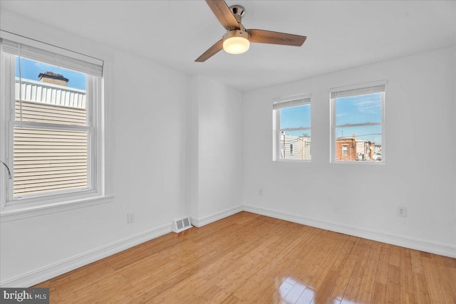 empty room with a ceiling fan, baseboards, visible vents, and light wood finished floors