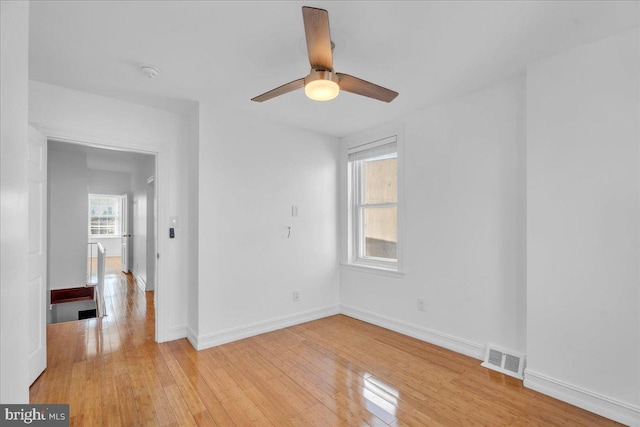 unfurnished room featuring light wood-style floors, visible vents, baseboards, and ceiling fan