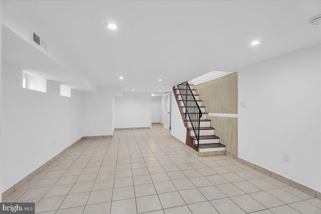 finished below grade area featuring light tile patterned floors, recessed lighting, visible vents, and stairs