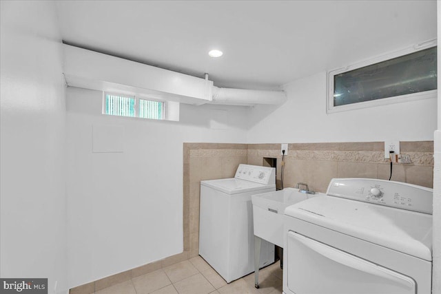 laundry area with tile walls, laundry area, washer and clothes dryer, and light tile patterned floors