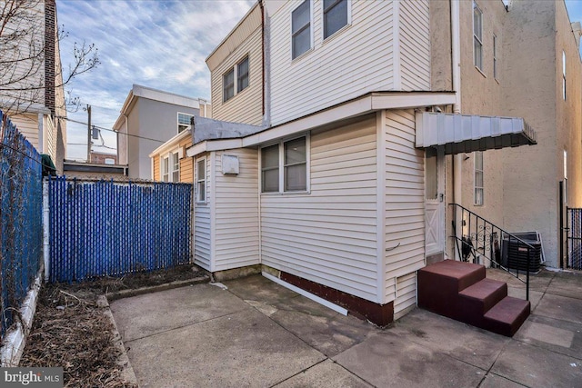 view of property exterior featuring a patio area, fence, and central air condition unit