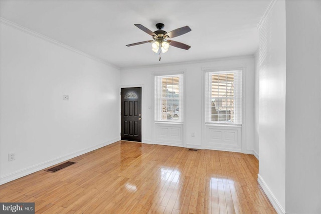 entryway featuring a ceiling fan, baseboards, visible vents, light wood-style floors, and ornamental molding