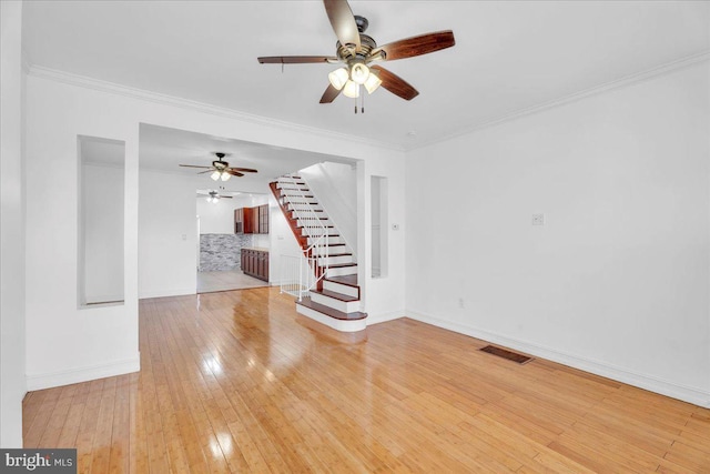 interior space with baseboards, visible vents, light wood-style flooring, stairway, and crown molding