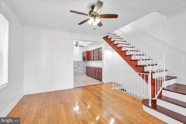 living room with baseboards, light wood finished floors, stairway, and crown molding