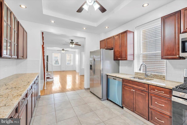 kitchen featuring a tray ceiling, stainless steel appliances, light tile patterned flooring, a sink, and recessed lighting