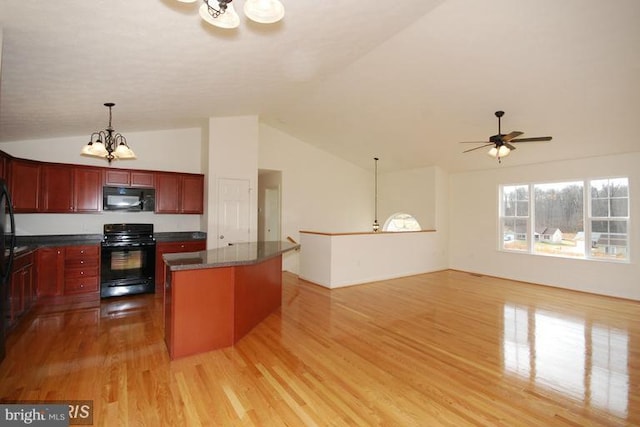 kitchen with reddish brown cabinets, a center island, light wood finished floors, dark countertops, and black appliances