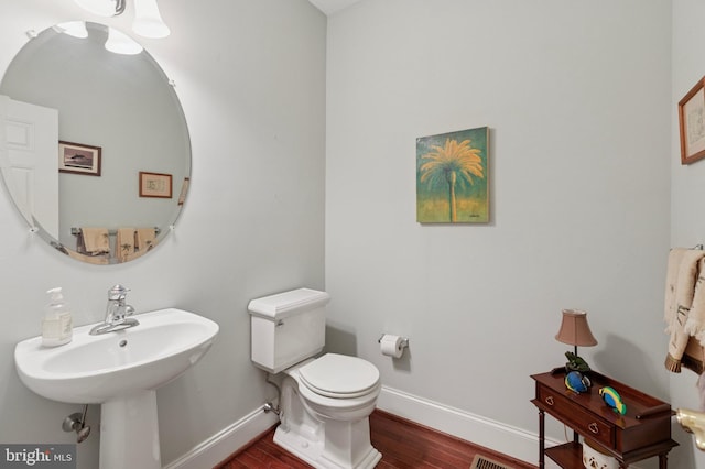 bathroom with toilet, baseboards, and wood finished floors