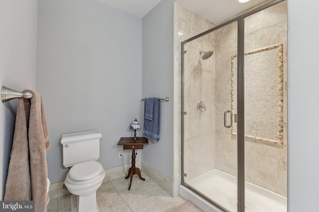 bathroom with a shower stall, toilet, and baseboards