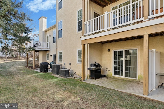 exterior space featuring a lawn, a patio, a chimney, cooling unit, and stucco siding