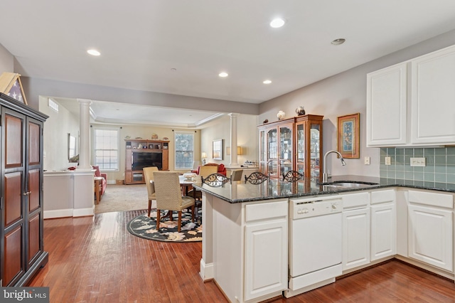 kitchen featuring decorative columns, dishwasher, open floor plan, a peninsula, and a sink