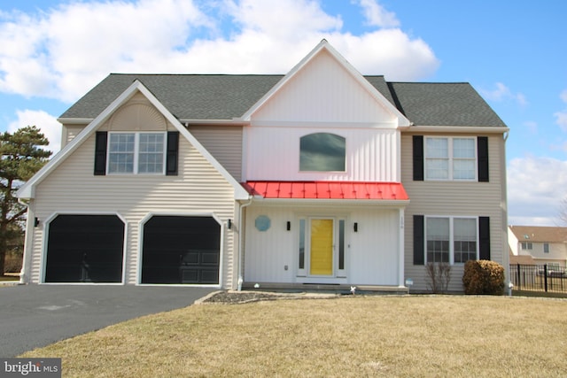 view of front facade featuring a garage, driveway, metal roof, fence, and a front lawn