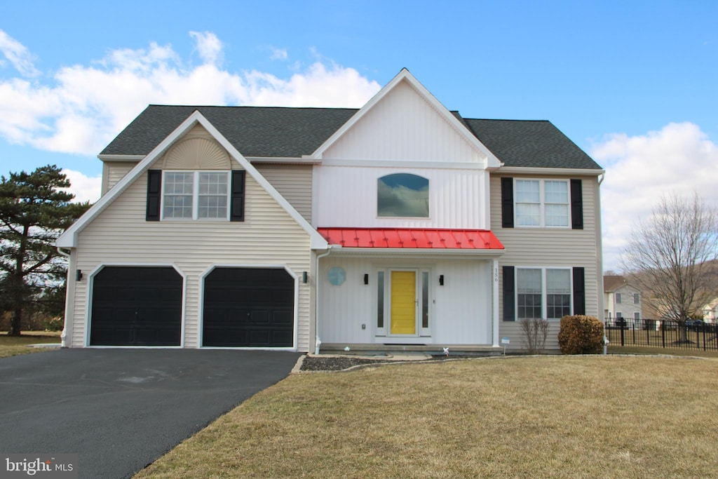 view of front of property featuring metal roof, a garage, fence, driveway, and a front yard