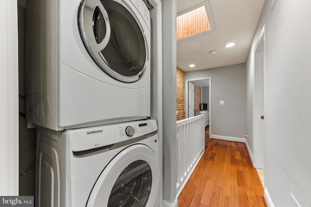 washroom featuring recessed lighting, laundry area, stacked washer / dryer, baseboards, and light wood finished floors