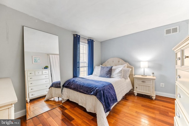 bedroom with wood-type flooring, visible vents, and baseboards