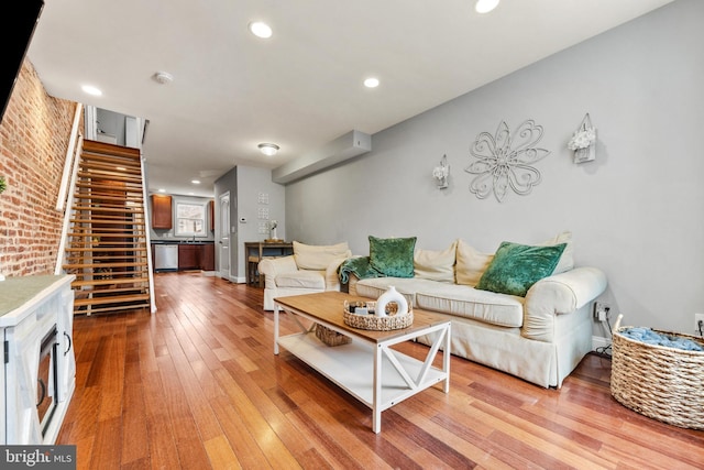 living area with stairs, brick wall, light wood-type flooring, and recessed lighting