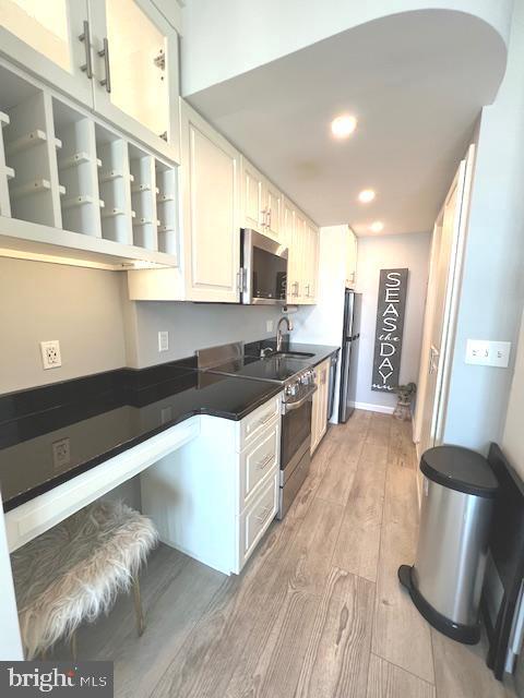 kitchen featuring light wood finished floors, recessed lighting, a sink, appliances with stainless steel finishes, and dark countertops