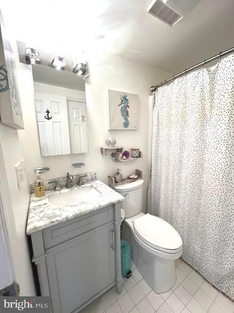 full bathroom featuring visible vents, toilet, a shower with shower curtain, tile patterned floors, and vanity