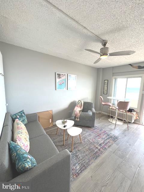 living area featuring a textured ceiling, a ceiling fan, and wood finished floors