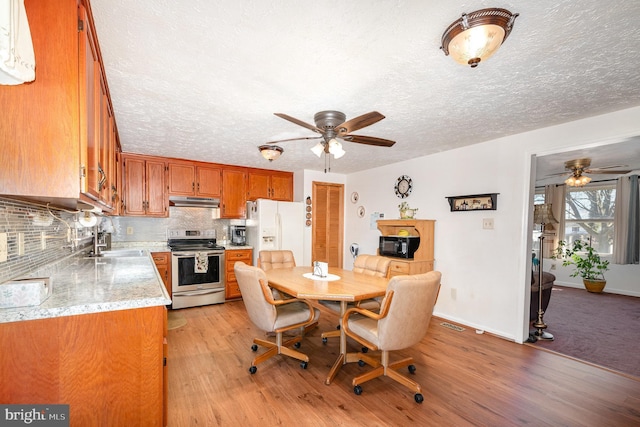 dining room featuring baseboards, a textured ceiling, light wood-style flooring, and a ceiling fan