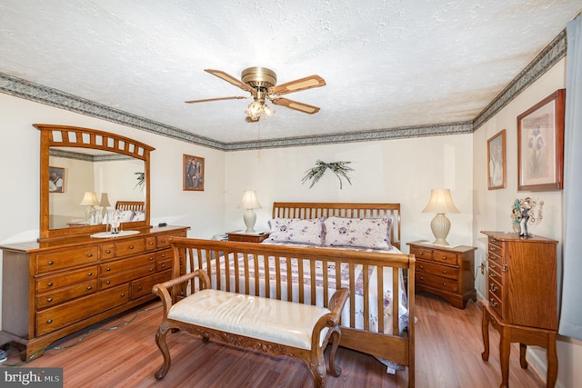 bedroom featuring a textured ceiling, wood finished floors, and ornamental molding