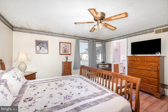 bedroom featuring visible vents, a textured ceiling, a ceiling fan, and wood finished floors