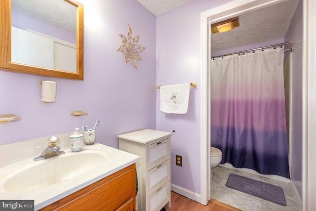 full bathroom featuring toilet, vanity, a shower with curtain, wood finished floors, and a textured ceiling