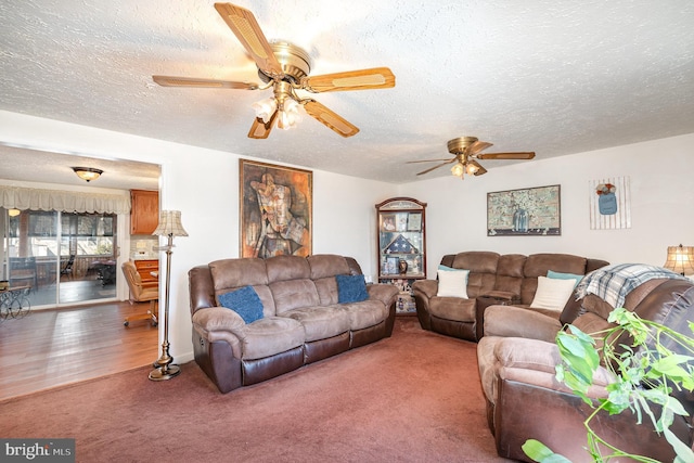 living room featuring ceiling fan, carpet, and a textured ceiling