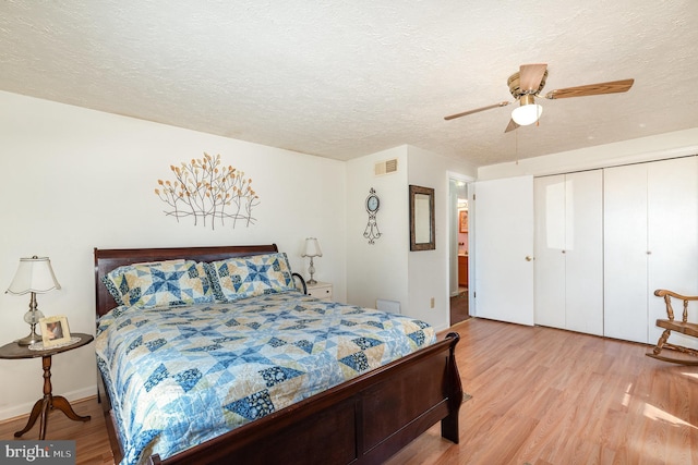 bedroom with light wood-style flooring, visible vents, a closet, and a textured ceiling