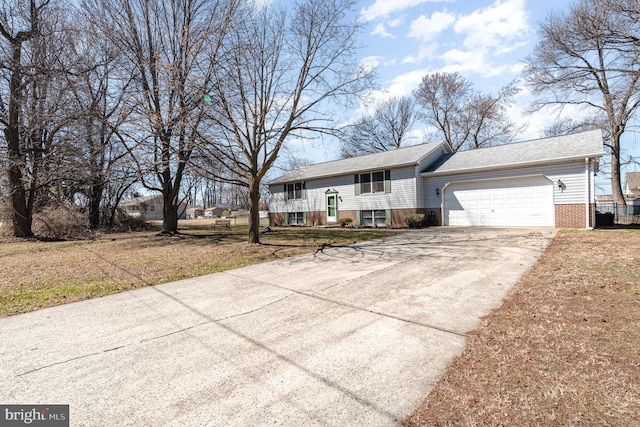 split foyer home with driveway, a front lawn, brick siding, and an attached garage