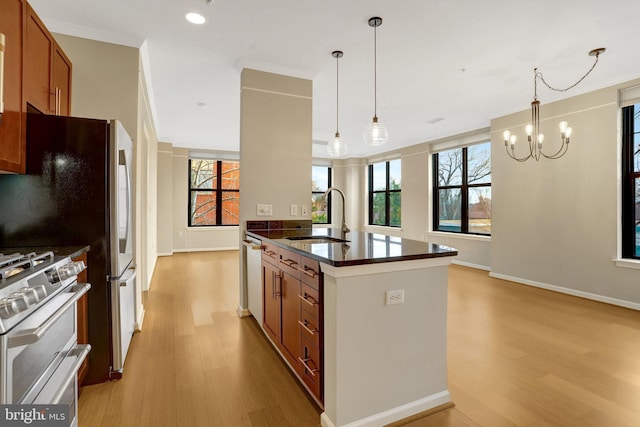 kitchen with a sink, light wood-style floors, appliances with stainless steel finishes, brown cabinetry, and plenty of natural light