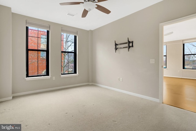 empty room featuring a healthy amount of sunlight, carpet, baseboards, and visible vents